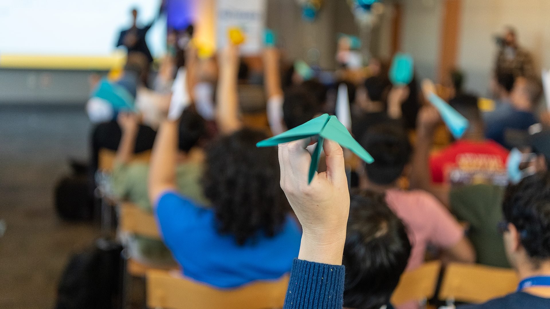 Crowd of people holding up paper airplanes